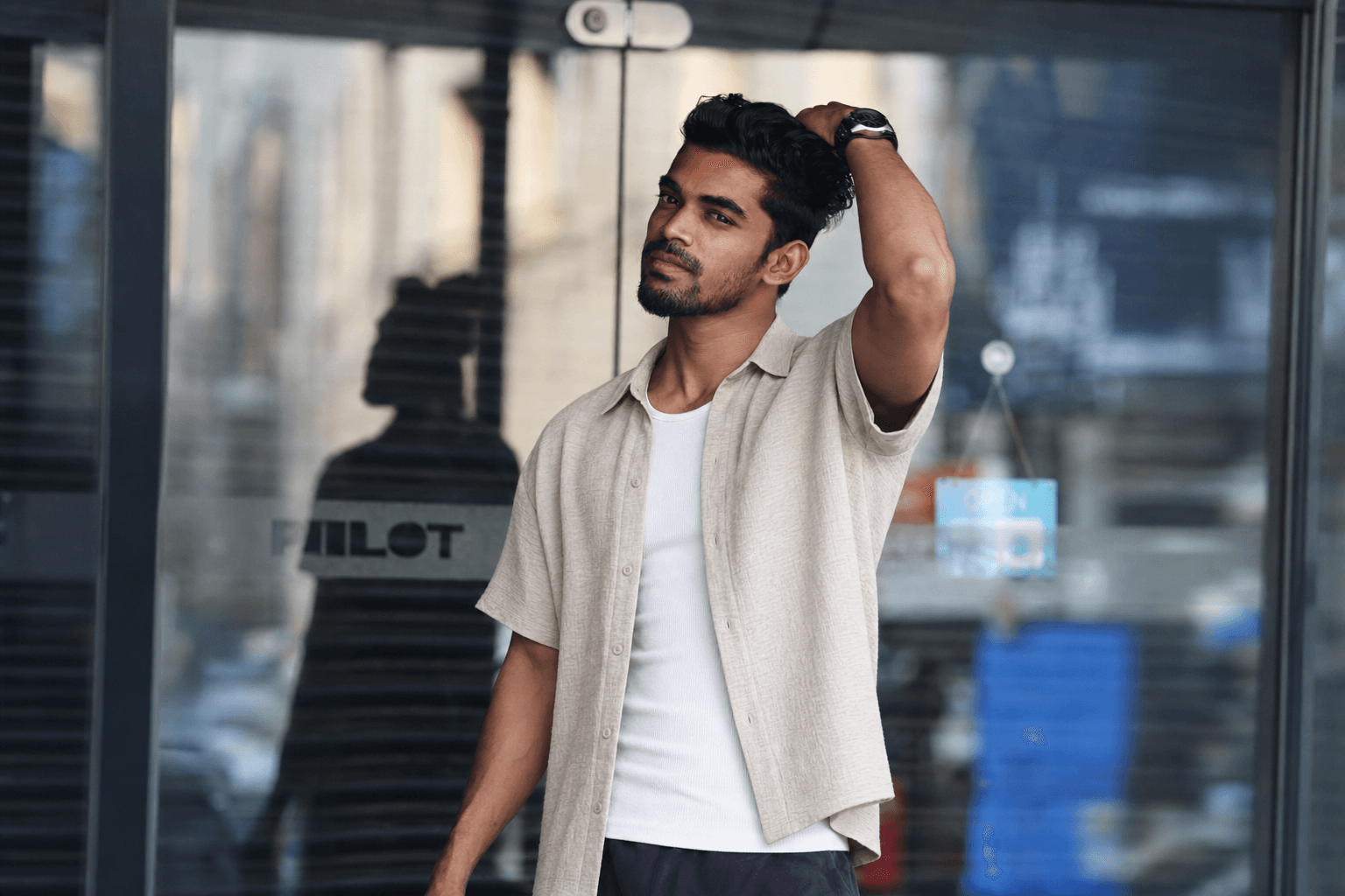After: the same supplied real man model in the unchanged photo, wearing a beige boxy short-sleeve shirt over a white ribbed top